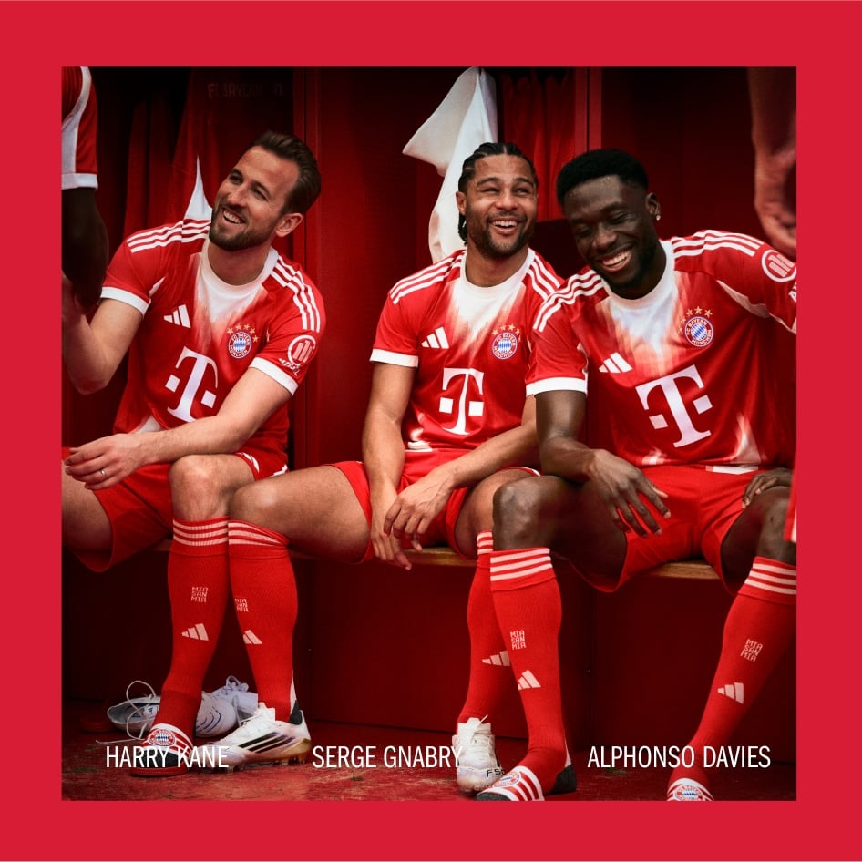 Drei Fußballspieler in roten Trikots sitzen zusammen, mit einem roten Vorhang oder Hintergrund.